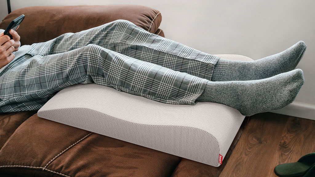 Patient en récupération à domicile avec pied surélevé sur coussin